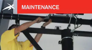 HiTech Maintenance service Technician in a yellow shirt performing maintenance on overhead sports equipment. A red banner at the top reads “MAINTENANCE” with HiTech’s logo.